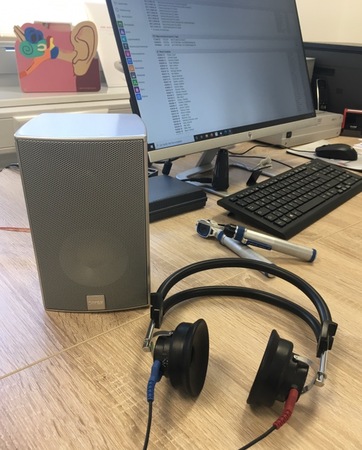Audiometrie-Arbeitsplatz mit Kopfhörer, Lautsprecher und Computer im Hörtestraum.